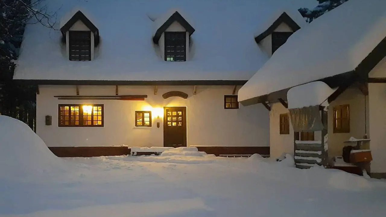 Snow-covered white chalet Maykiss in Hakuba at dusk, with lit windows (our own photo)