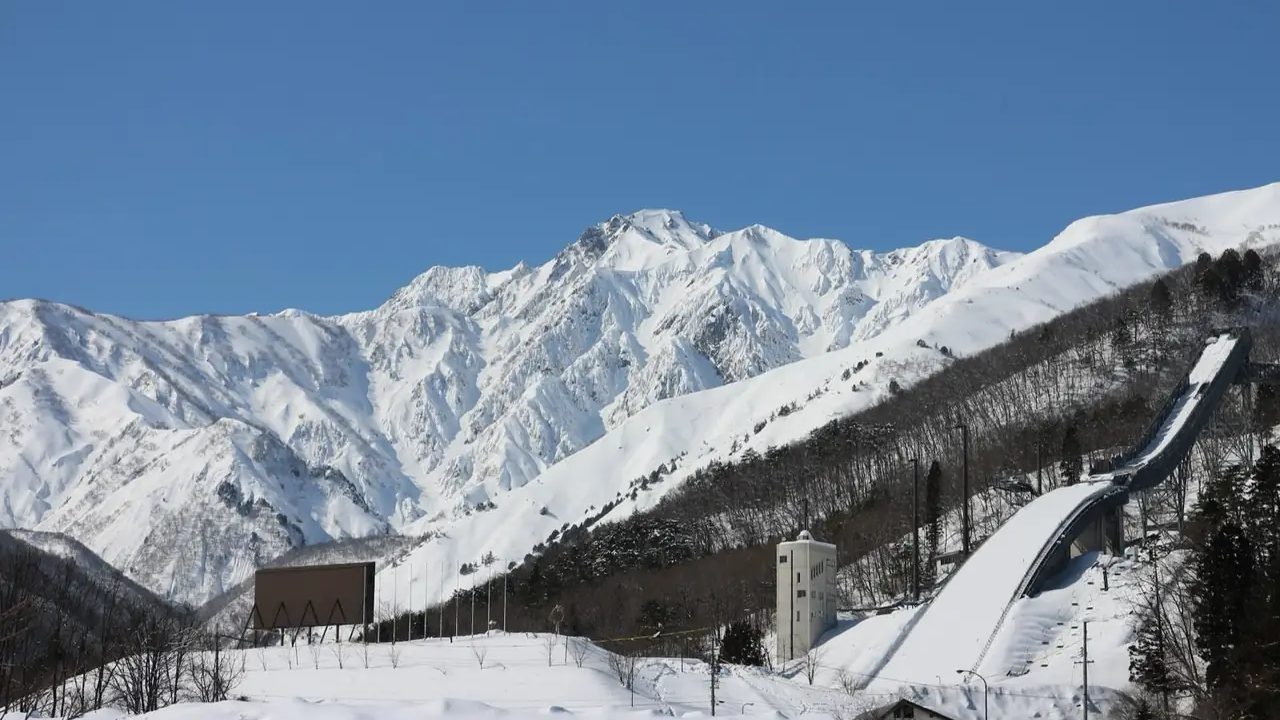 晴朗冬日里，白马的跳台滑雪场和身后积雪的北阿尔卑斯山